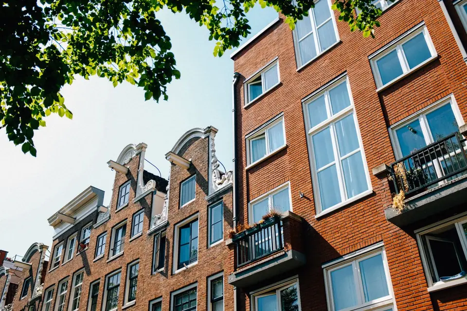 Bakstenen gevels met balkons en trapgevels in Amsterdam, gezien vanaf de straat