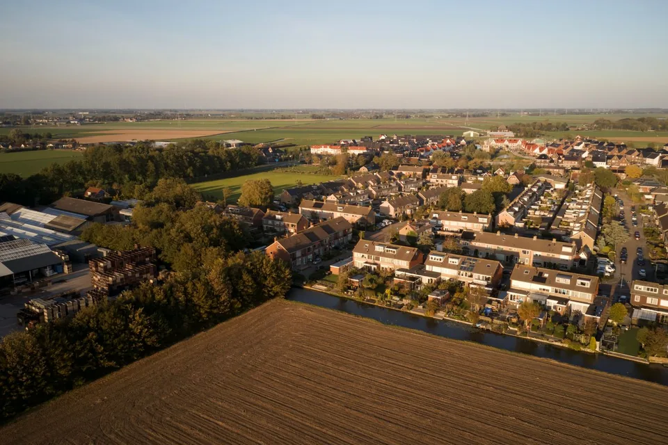 Luchtfoto van een dorp met eengezinswoningen aan de rand van de polder