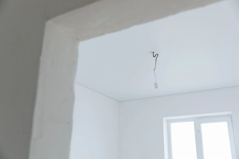 Lege kamer met strak afgewerkte witte wanden en een losse plafondaansluiting