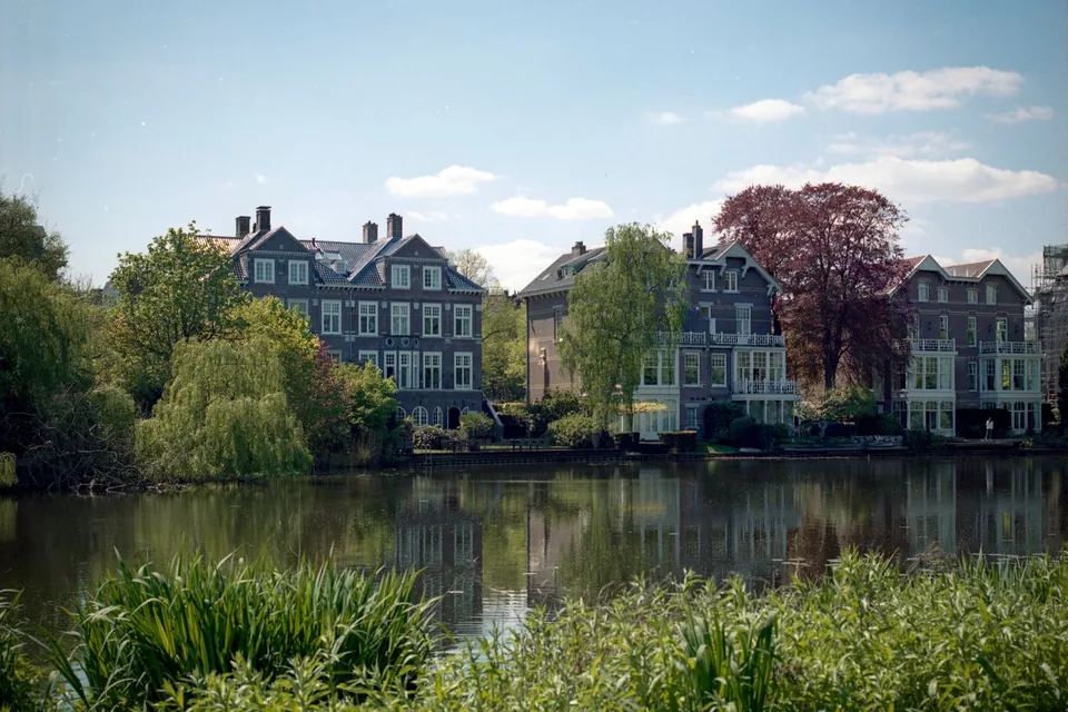 Statige woonhuizen tussen groen aan de rand van een vijver